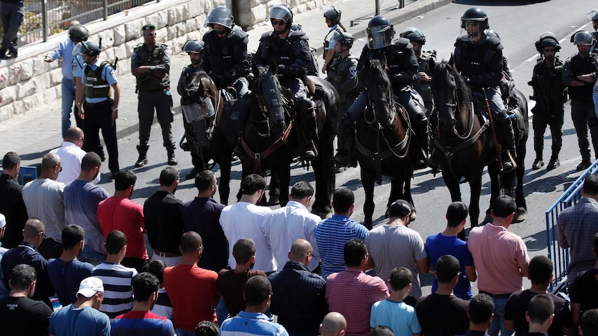 Israeli police stand guard as Palestinian Muslims pray on the streets outside the Al-Aqsa mosque