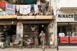 A man walks out of a shop in Beirut with clothing hanging over the balcony.