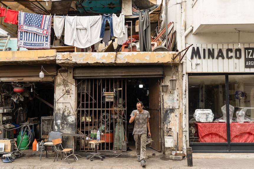 A man walks out of a shop in Beirut with clothing hanging over the balcony.