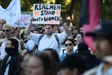 Man holds sign saying 'real men stand with women' among other protesters at the violence against women rally in Sydney.