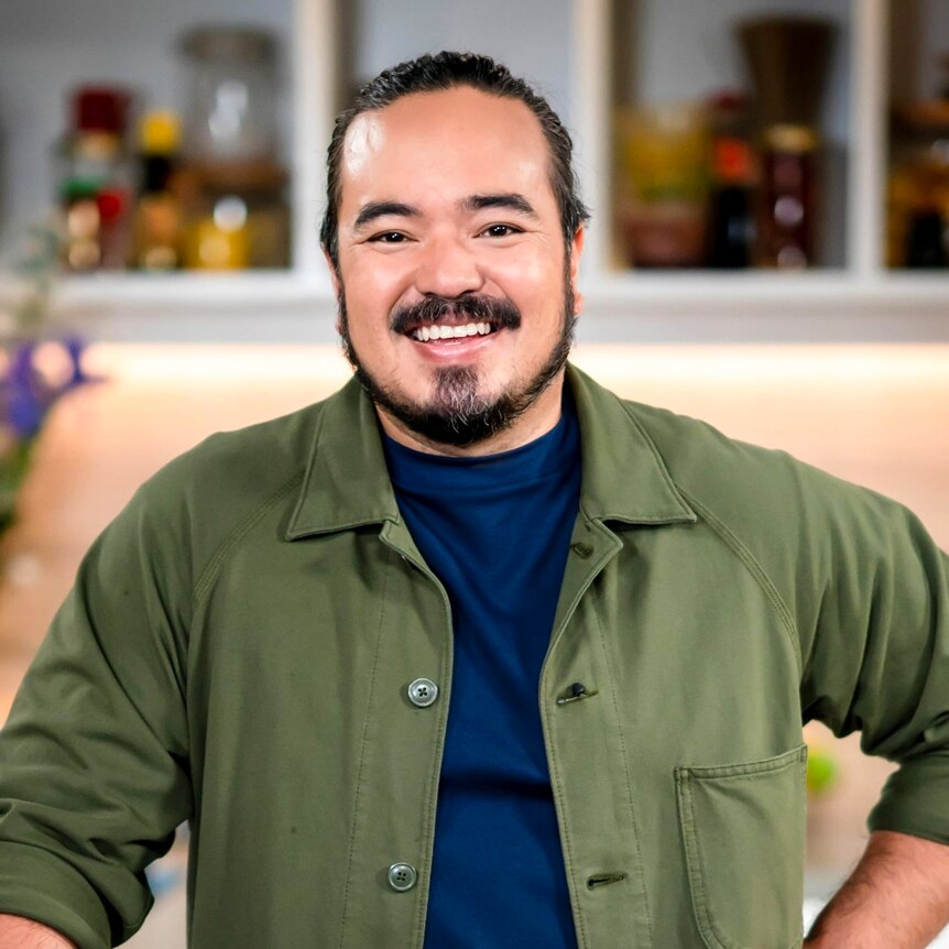 Reality TV cook Adam Liaw smiles inside his kitchen.