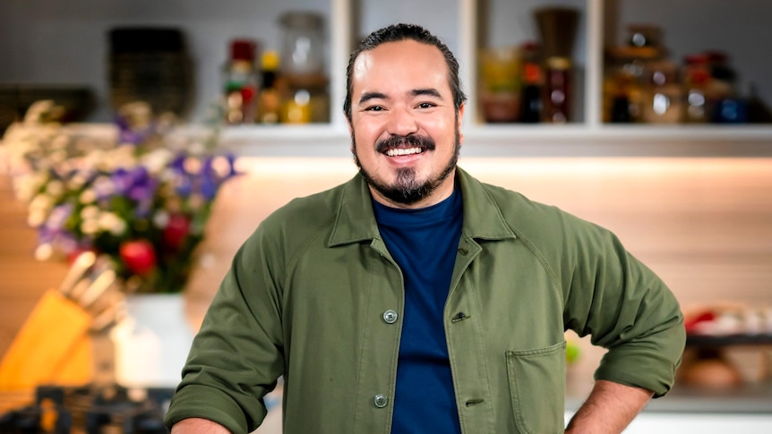 Reality TV cook Adam Liaw smiles inside his kitchen.