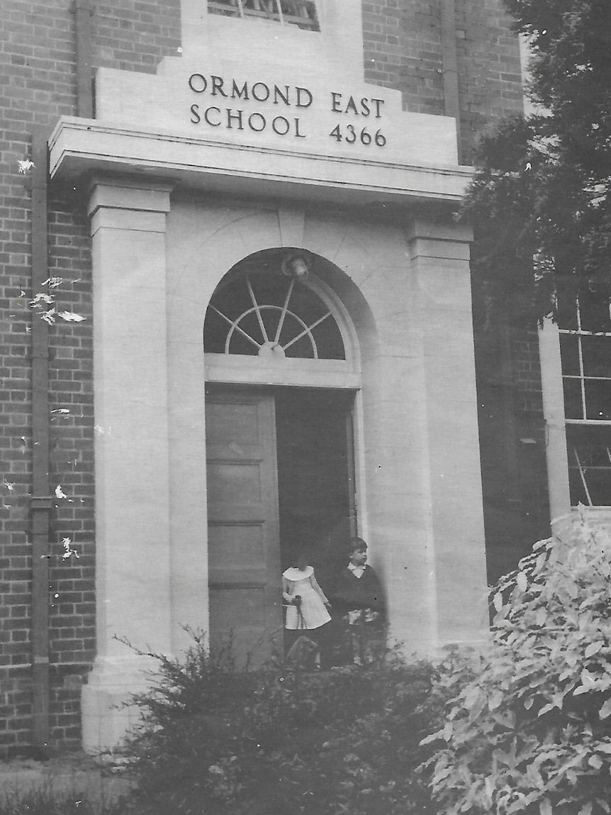 black and white photo of two children in front of the ormond east primary school doorway