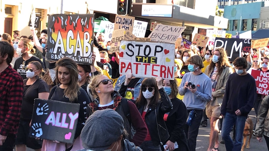 A large crowd marching through the streets holding banners