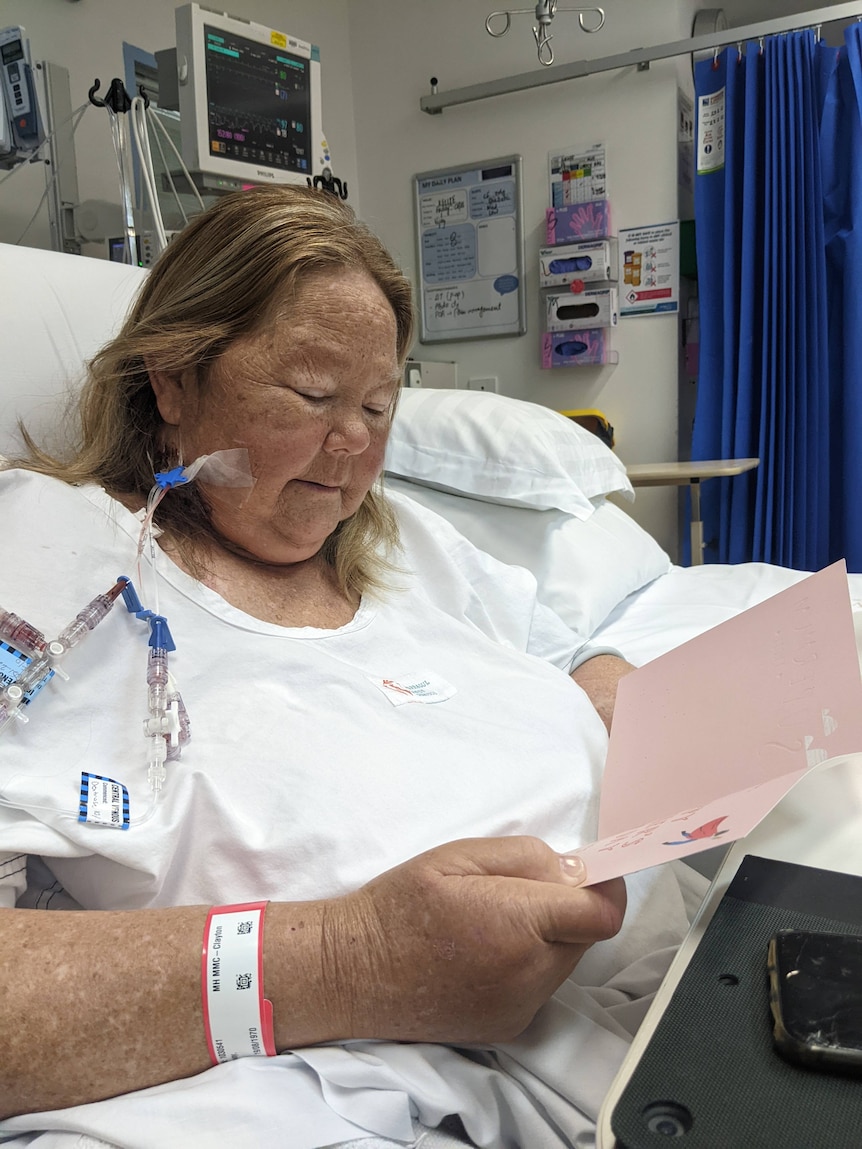 Kellie Ottaway sitting in a hospital bed reading a card.
