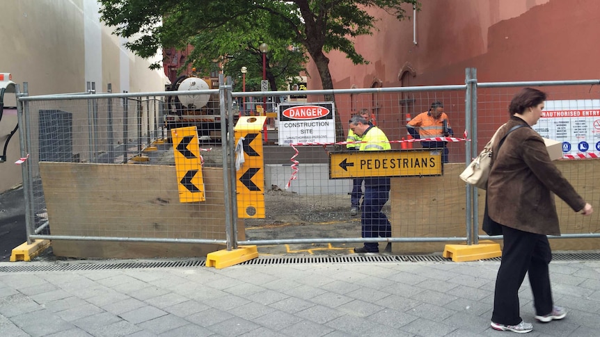 A fence with a construction sign and men working behind it