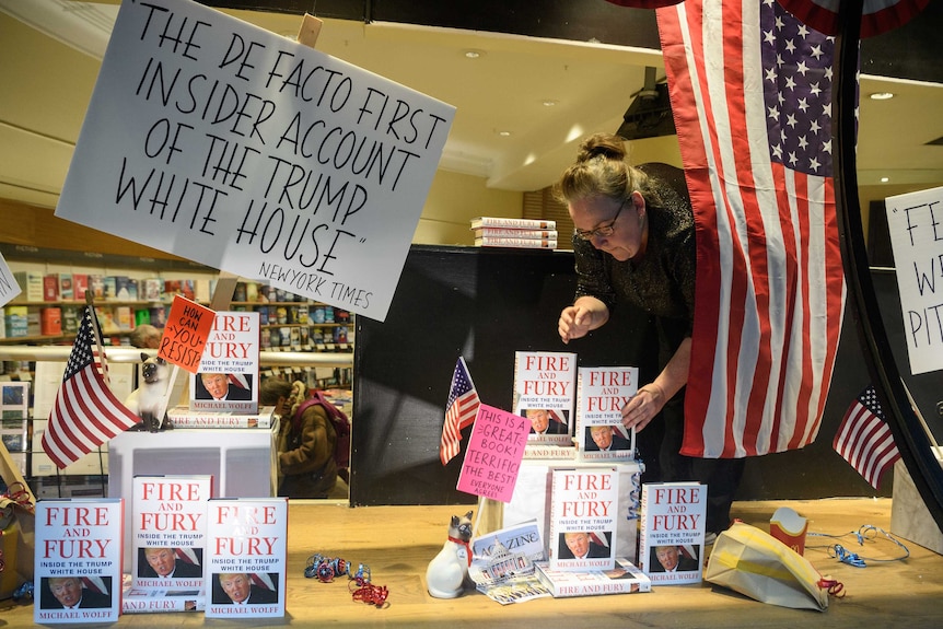 A woman adjusts copies of Fire and Fury on sale inside a bookstore.