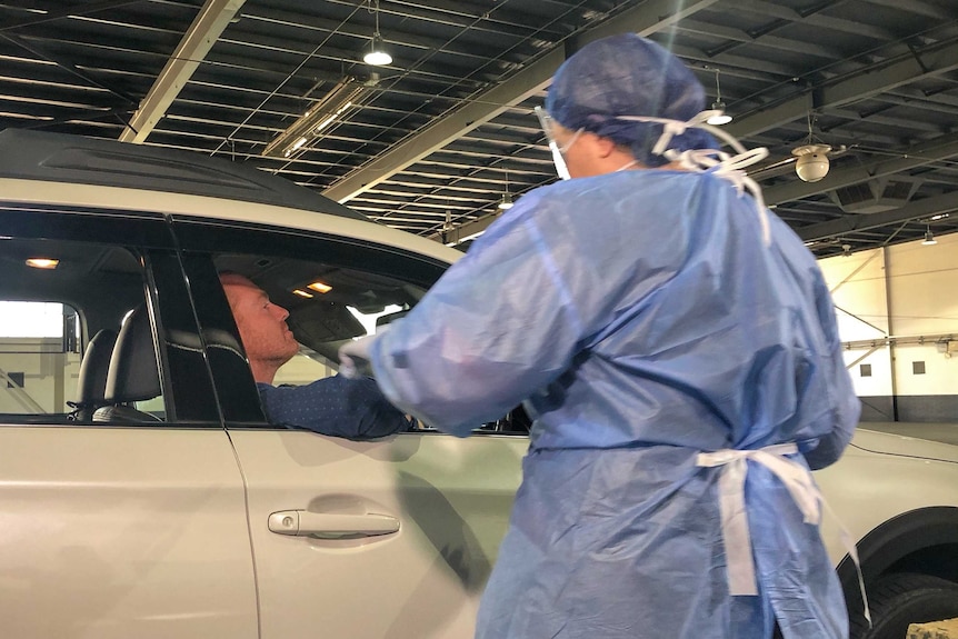 A man in a white car is tested by a nurse.