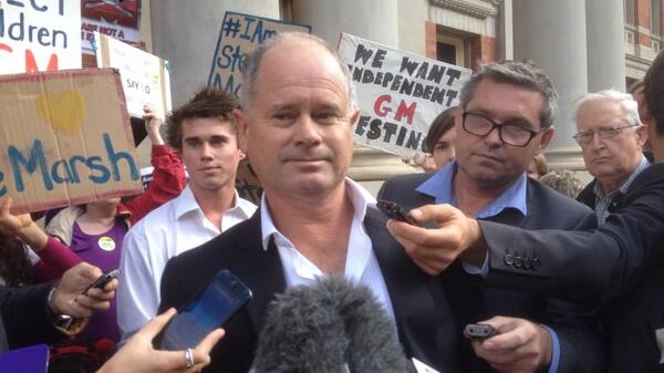 Michael Baxter surrounded by media