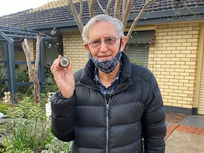 A man stands holding the 100 year old pocket watch that belonged to his father