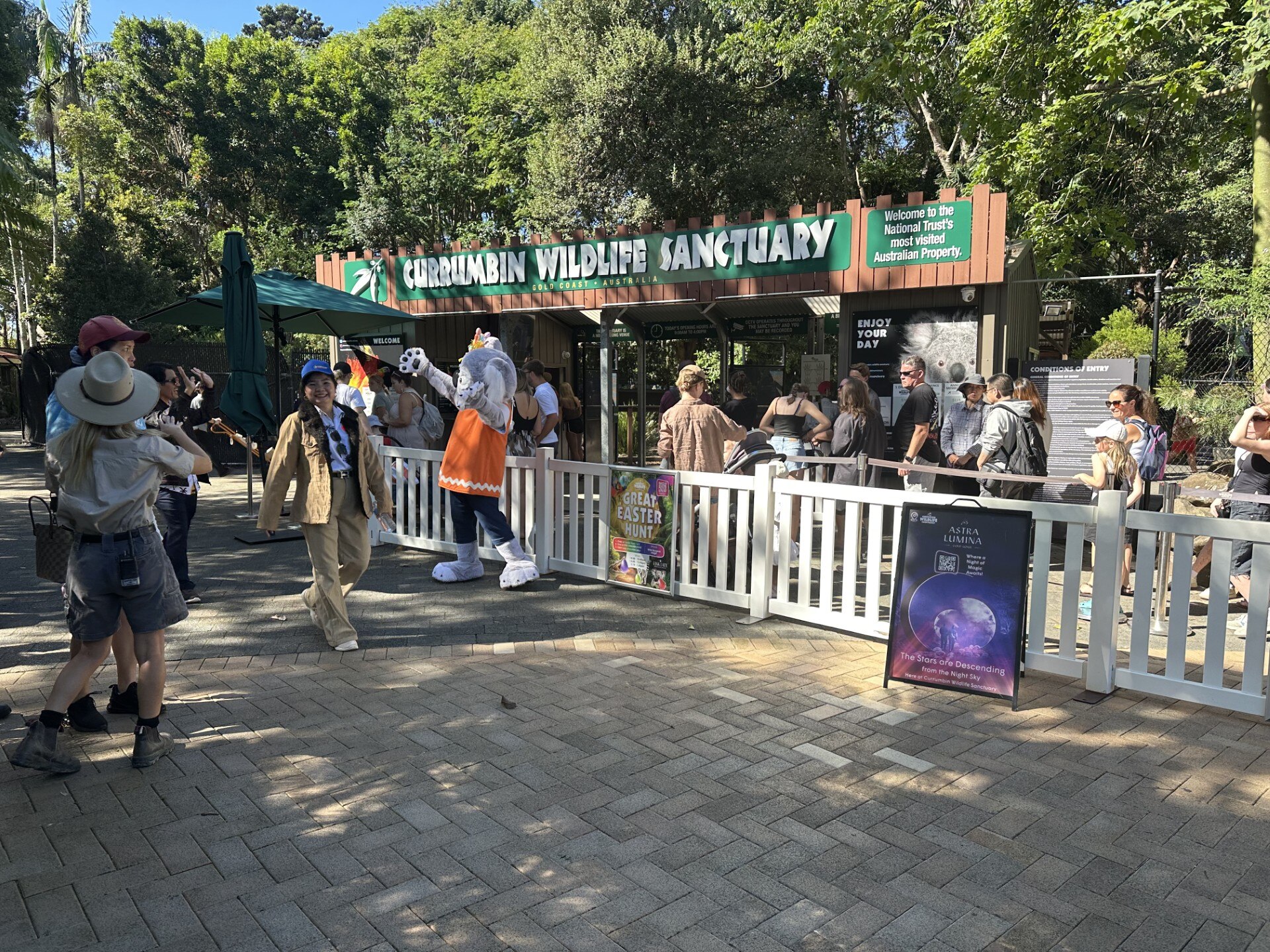 People mill around the paved entrance to a leafy animal sanctuary.