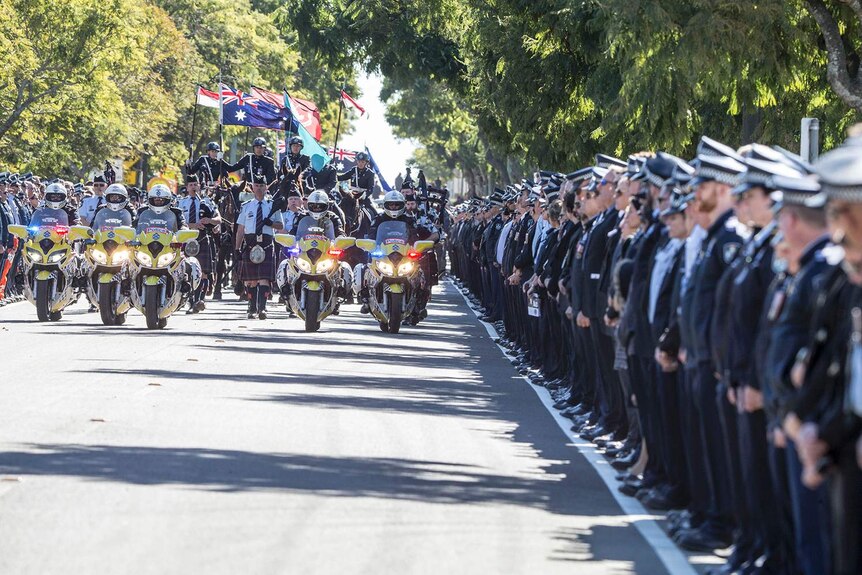 Police line the street in a guard of honour for the funeral procession led by police on motorcycles and horses and pipers