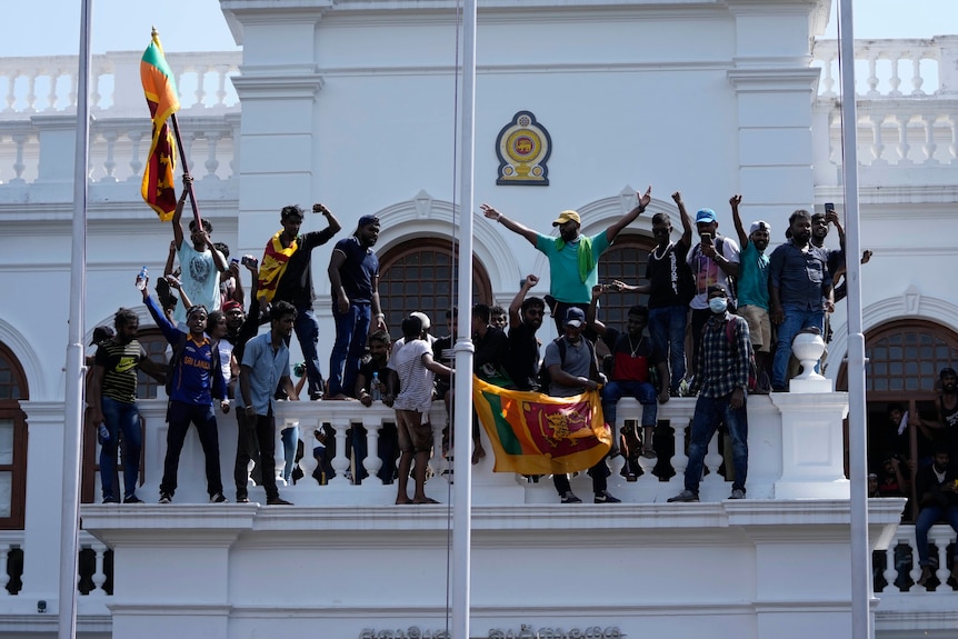 About 20 protesters pose in celebration after scaling a government office in Sri Lanka. 