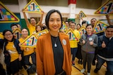 A woman stands smiling in front of a group of her supporters
