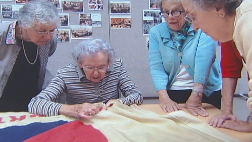 Woman restoring a World War One banner to be returned to the RSL