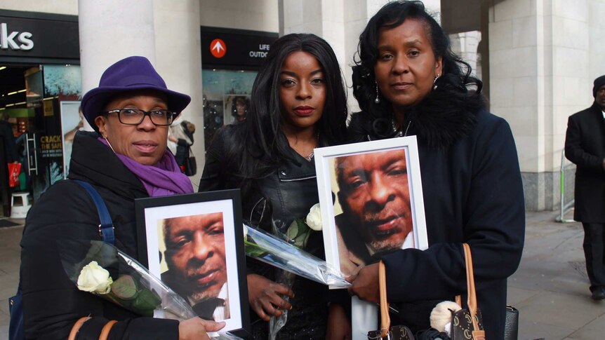 Three women hold up photos of a man killed in the fire.