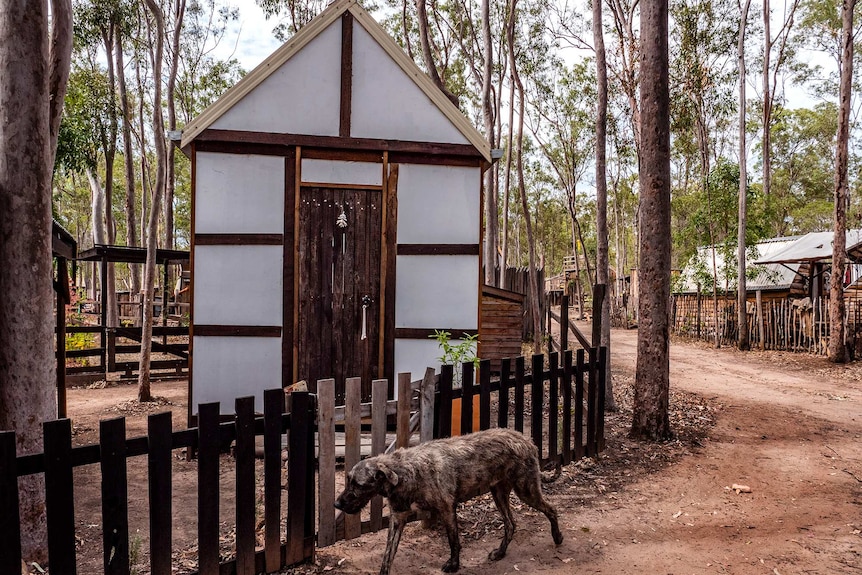 A small tudor style hut with a dog walking past.