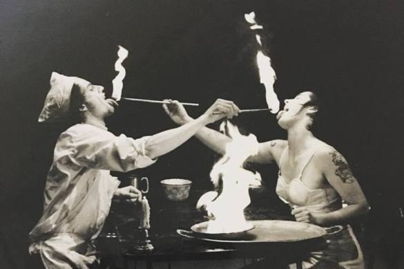 A black and white photograph of two circus performers feeding each other fire in Rock n Roll Circus' Body Slam