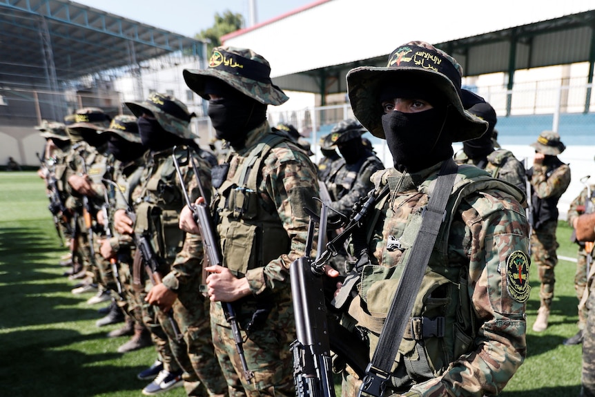 PIJ fighters stand in military gear holding up rifles.