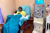 An Aboriginal woman sits at a dialysis chair with a blanket over her. 