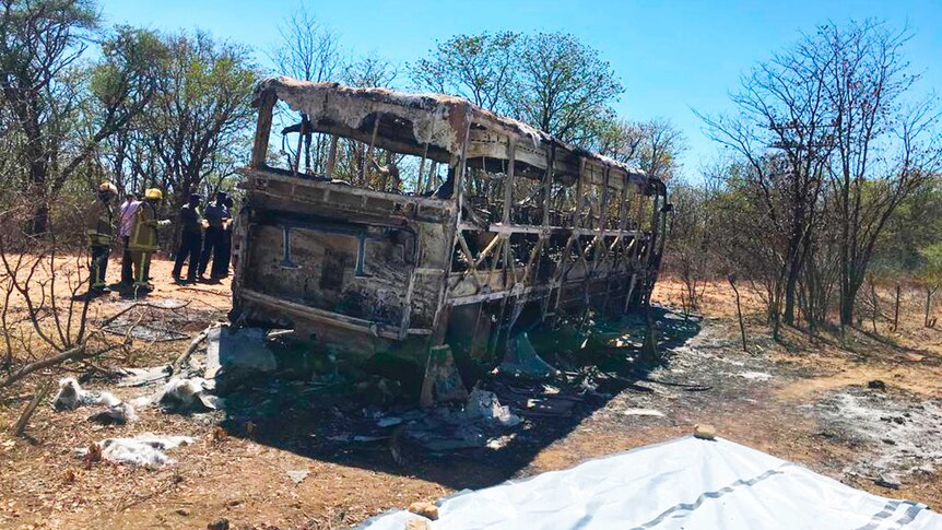 Emergency services stand near to a burnt out bus after a bus accident in Zimbabwe.