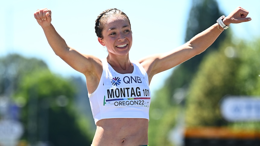 An Australian female race walker raises her arms as she crosses the finish line at the world championships.