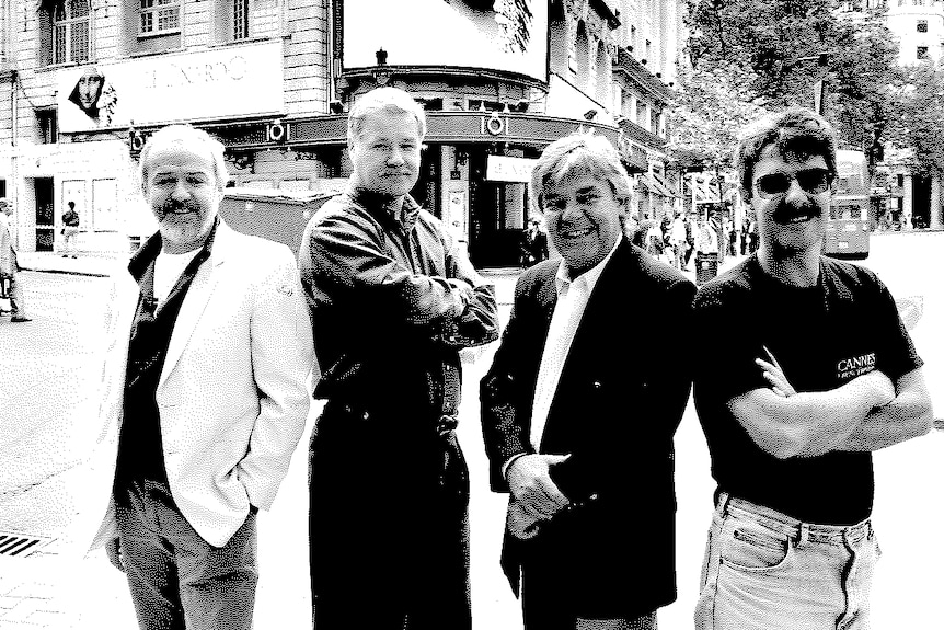 Four men standing out the front of a theatre