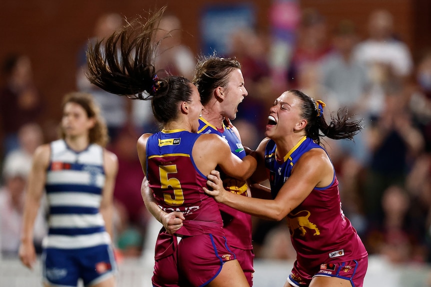 Lions players celebrate a goal with disappointed Cats players in the background