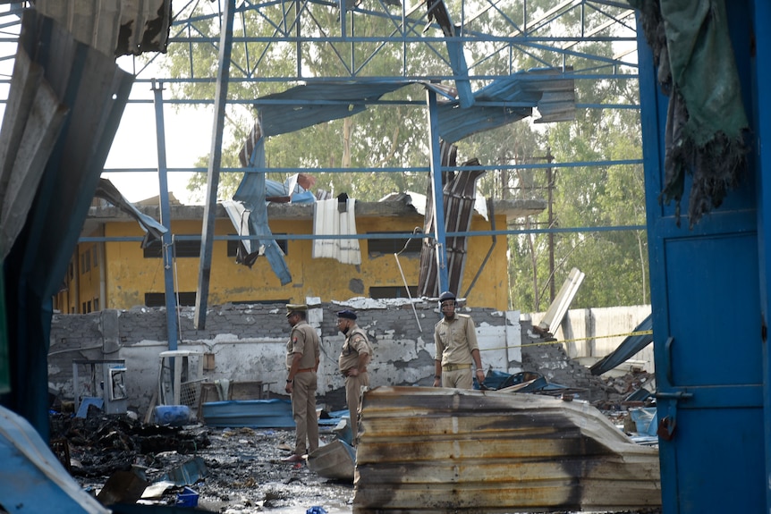 Policemen inspect the site of a factory fire