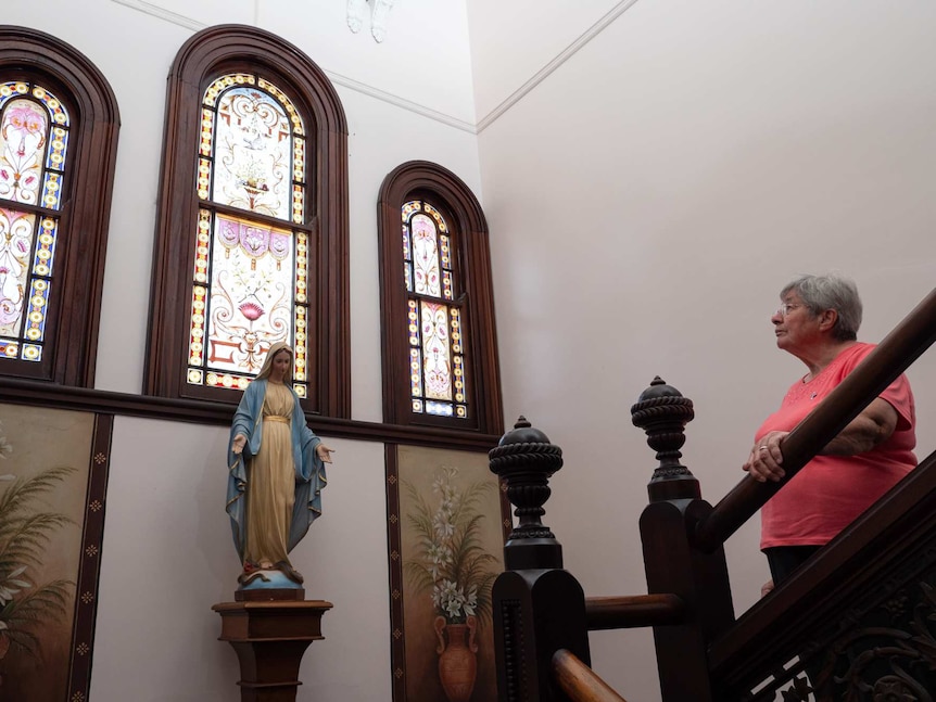 Sister Patricia Powell looking at a stained-glass window in a stairwell at Saint Joseph's Mount.
