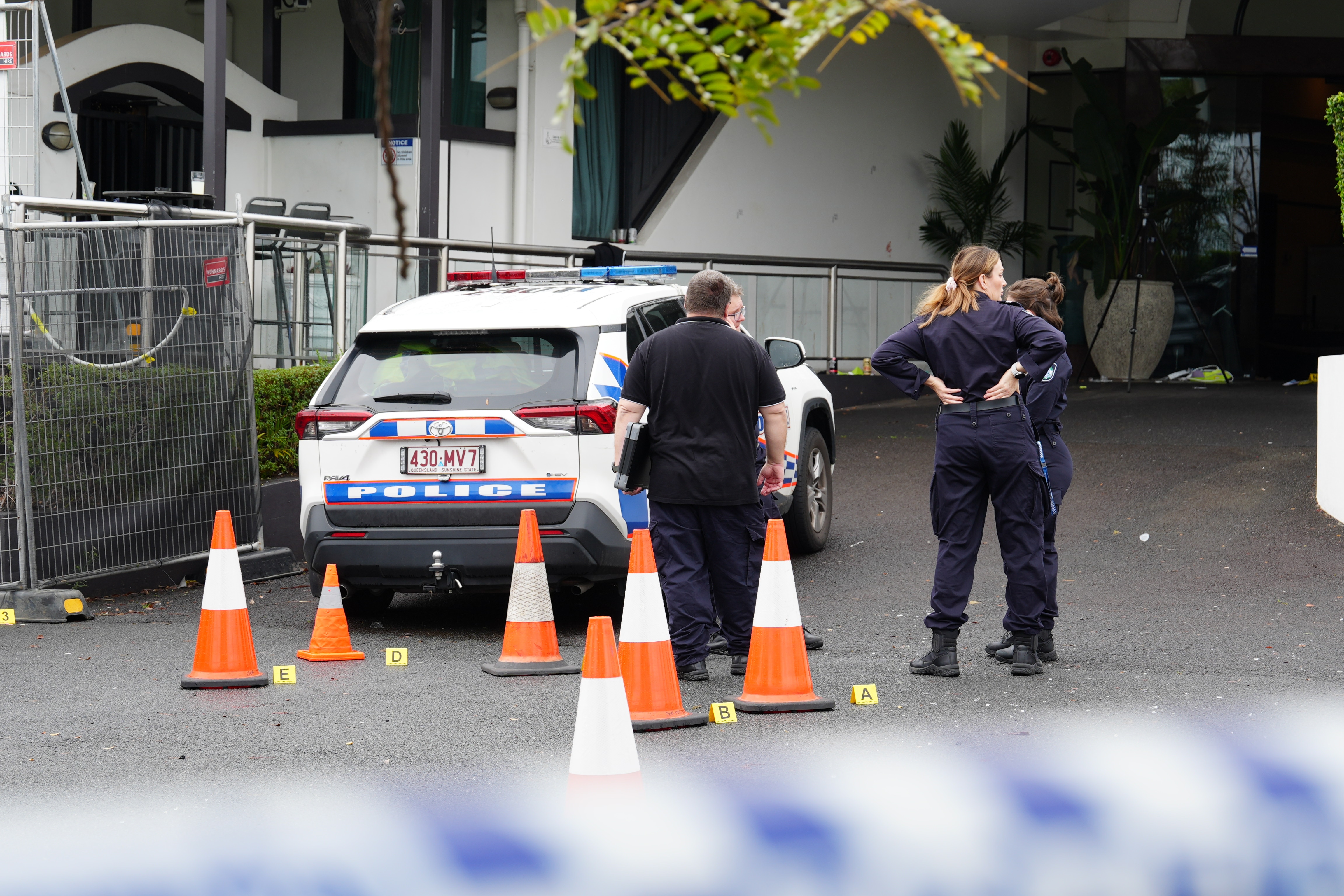 Police officers, a car and orange cones outside a venue.
