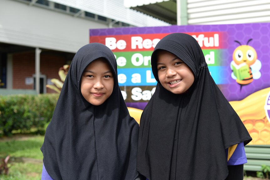 Two primary school-aged students wearing hijabs stand in front of Balaclava State School.