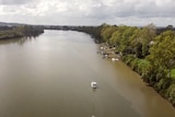 A wide brown river with a handful of boats