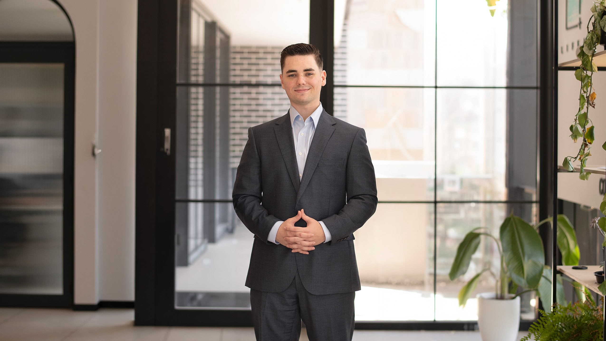 A man in a suit stands smiling at the camera.