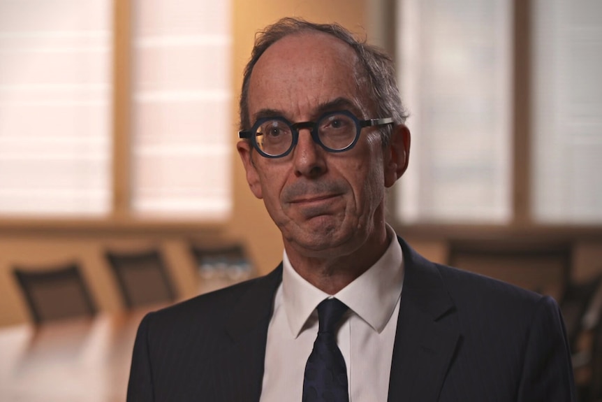 Man wearing a suit sitting in an office meeting room.