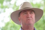 Barnaby Joyce, wearing his akubra, looks off camera. There is a worried expression on his face