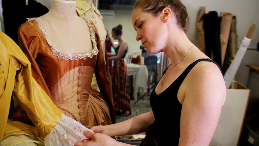 a woman looking at a colonial-era dress