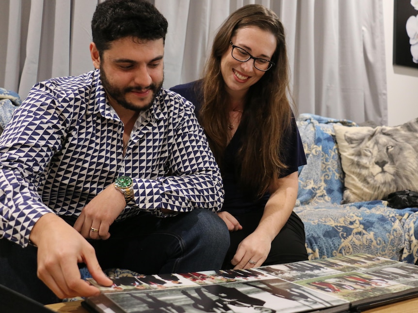 A couple sit on the couch looking at wedding photographs