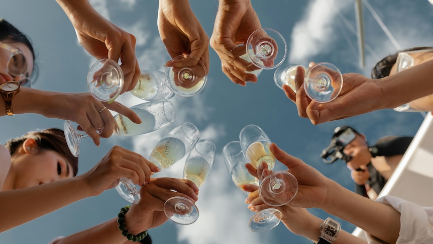 A group of people raise champagne flutes in a toast.