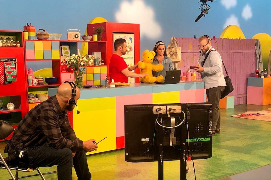 Behind the scenes on the Play School set. Producer talks to the presenters and stage manager watches what is going on.