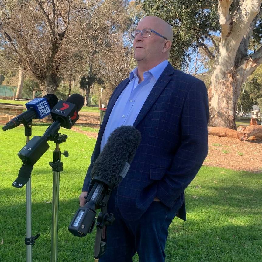 David Rigdway standing on green lawn behind microphones