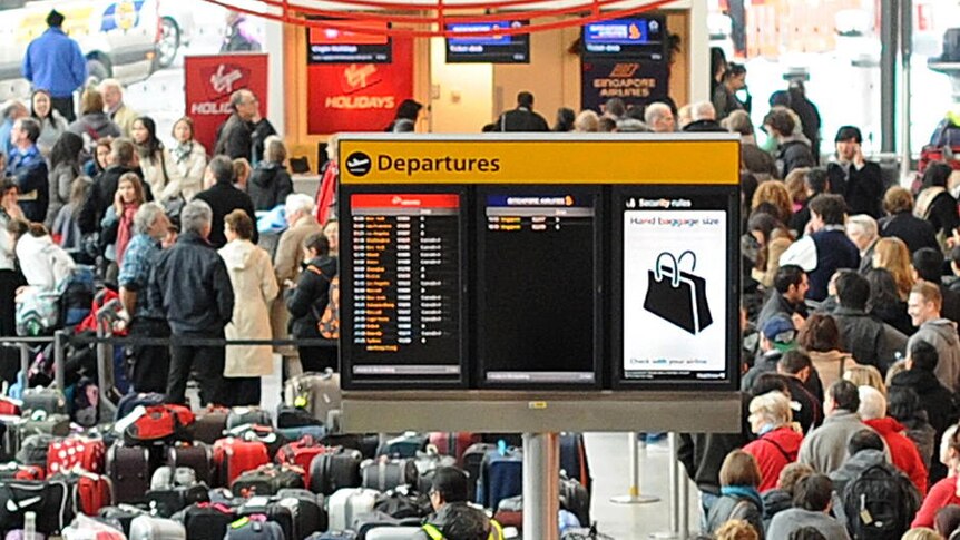 Airline passengers queue beside rows of luggage