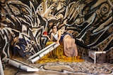 A art work featuring graffitied walls and a mannequin lounging