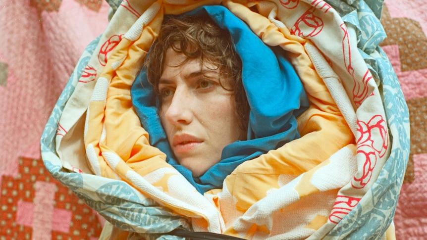 Aldous Harding's head pokes out of a multilayered quilt