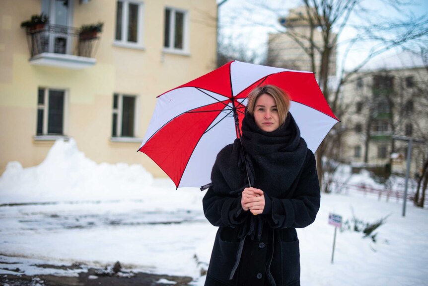 Maria holds a red and white umbrella.