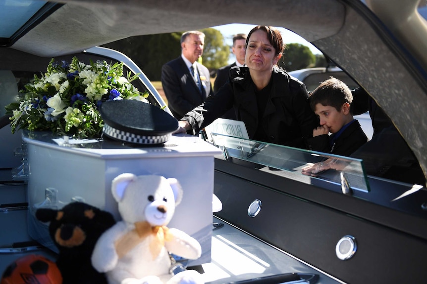 Senior Constable Brett Forte's wife Susan and son Brodie touch the casket after his funeral service in Toowoomba