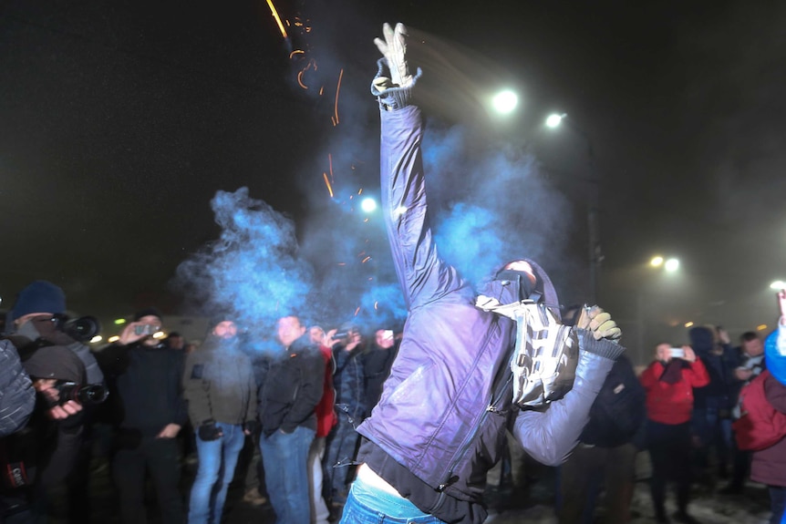 A protester throws a smoke grenade during a rally in front of the embassy of Russia in Kiev, Russia.