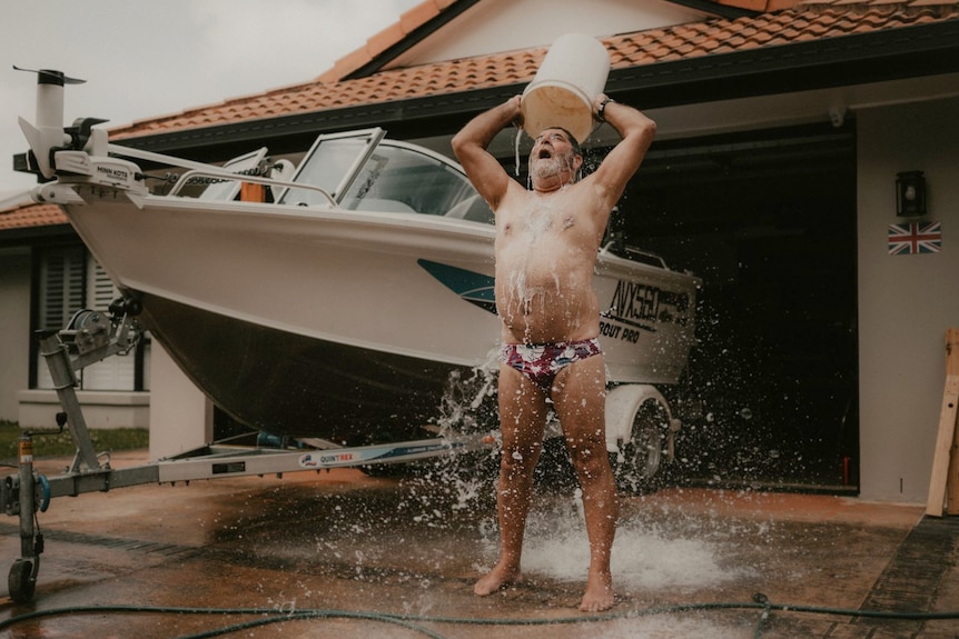 Man wearing 'budgie smugglers' tipping bucket over his head