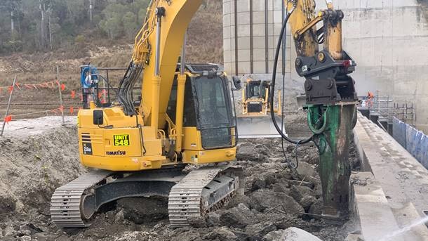 A yellow digger drills down into the Paradise Dam wall during essential works in August 2020.