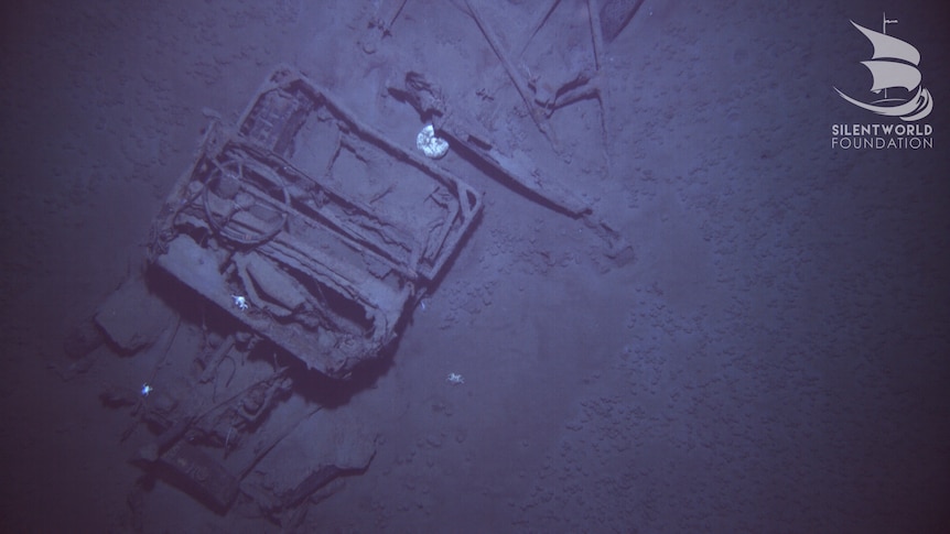 An old jeep is seen on the seabed.